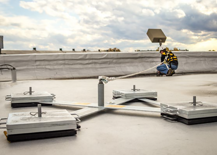 Facility manager inspecting rooftop fall protection accessories including guardrails and anchor points