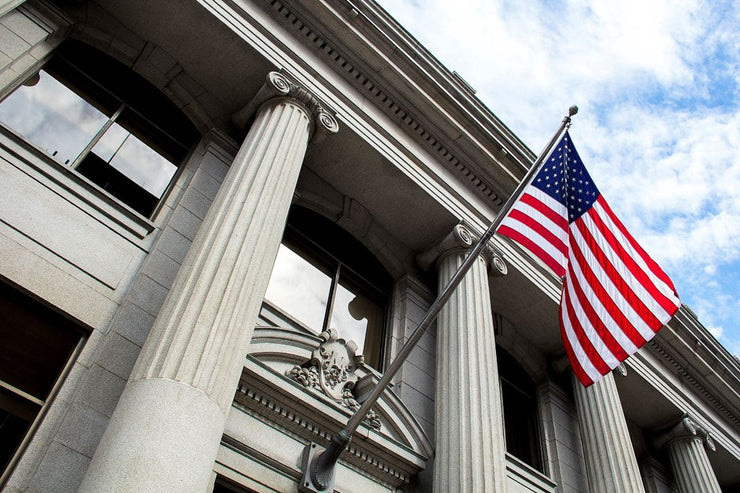 US government building featuring a classical columned facade with an American flag flying in front