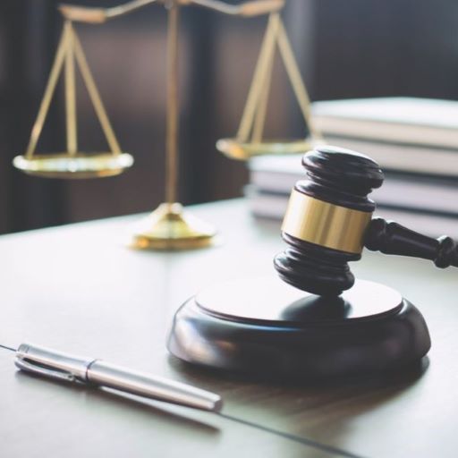 Gavel on wooden base with brass scales of justice.