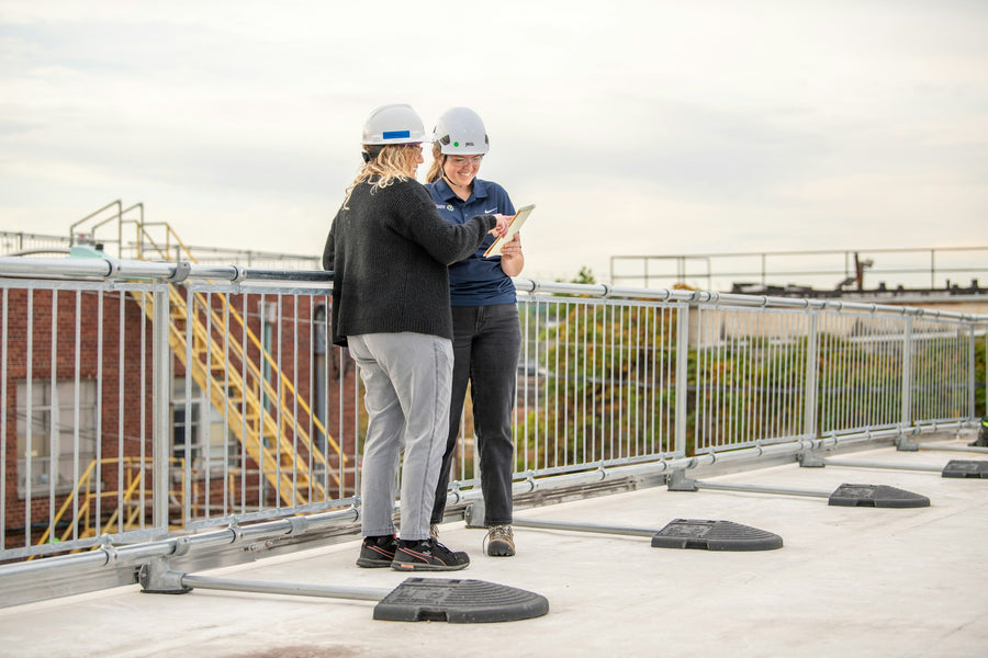 Workers on roof wearing safety helmets with side guard rails for construction fall protection
