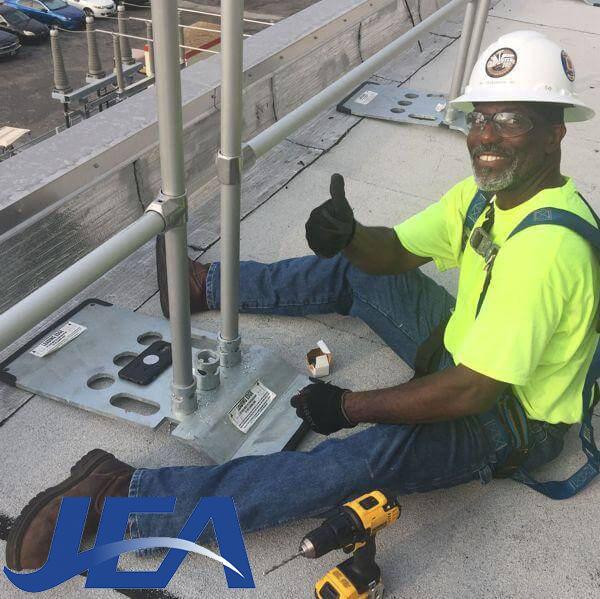 Worker installing Safety Rail Source OSHA-compliant roof edge fall protection guardrails at the Jacksonville Electric Authority (JEA) Power Plant in Jacksonville, FL.