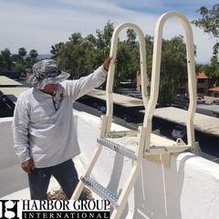 Worker installing a safety ladder with logo overlay of Harbor Group International