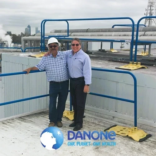 Two men standing on a commercial rooftop with Danone logo overlay