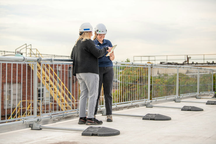 Workers on roof wearing safety helmets with side guard rails for construction fall protection