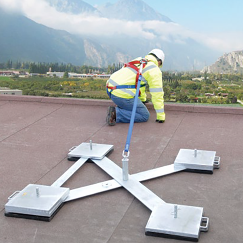 Worker on a rooftop connected to a Kee Anchor fall protection anchor from Safety Rail Source
