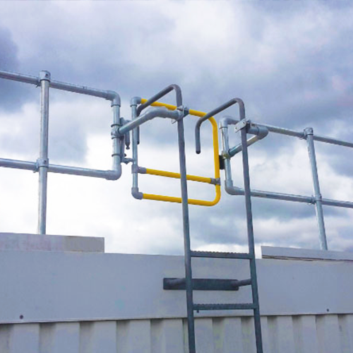 Exterior ladder leading to a roof with a yellow gate and rooftop railing.