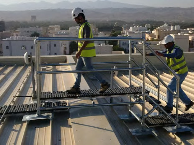 Two construction workers using a Kee Walk ramp on a rooftop.