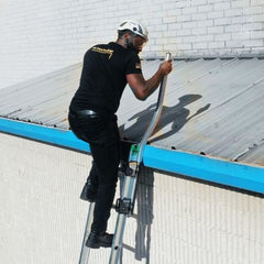 Man climbing an extension ladder onto a roof