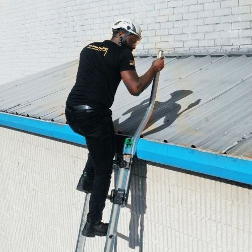 Man climbing an extension ladder onto a roof