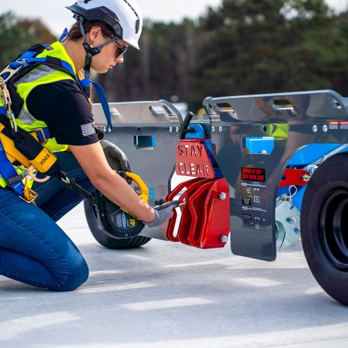 Worker performing fall protection maintenance inspection on rooftop guardrail system