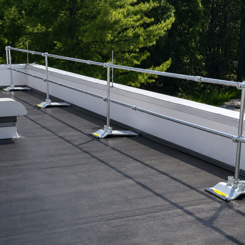 Metal safety railing system on a rooftop with green trees in the background