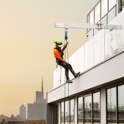 Worker suspended over the side of a commercial highrise using Sky Davit Arm, harness and lifeline.