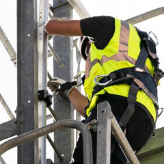 Man wearing harness attached to a fixed ladder lifeline for fall protection