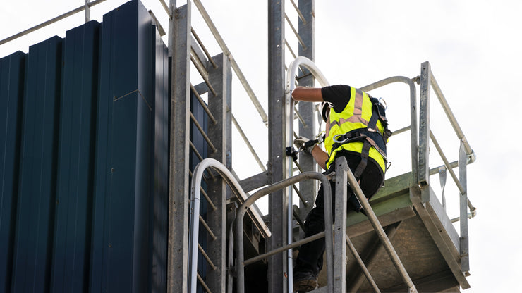 A worker climbing up a ladder to the roof