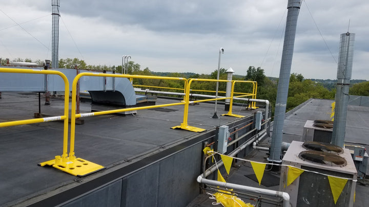 Yellow safety guardrail system installed on a commercial rooftop next to an HVAC unit