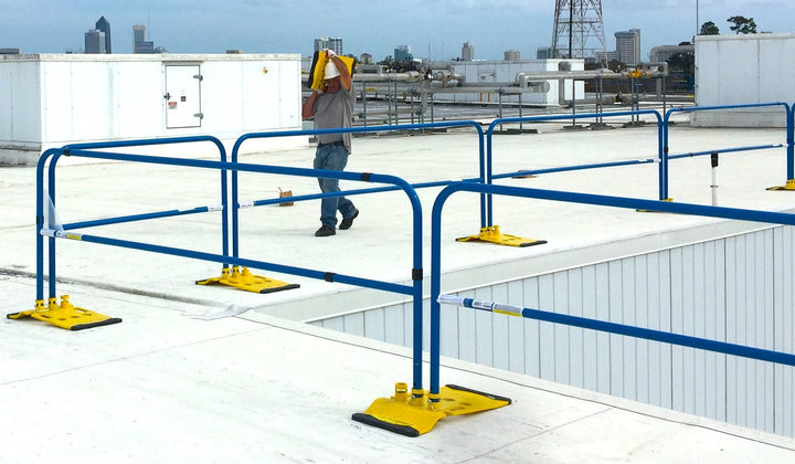 A worker walking on the roof with guardrails for fall protection, carrying a 58 lbs.base 