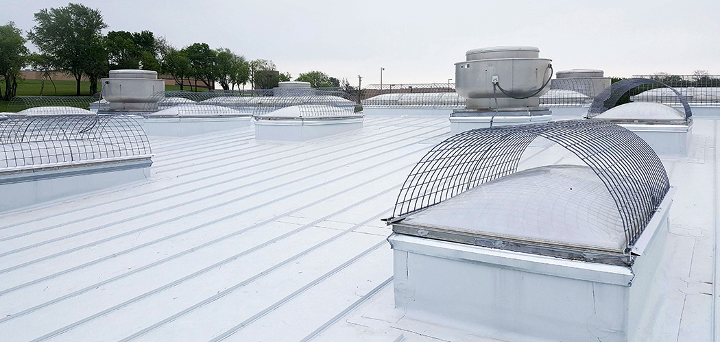 Roof top with HVAC units and metal grates on a clear day