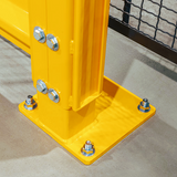 A close-up of a bright yellow metal support post anchored to a square base plate with multiple silver bolts and nuts, set on a concrete floor.