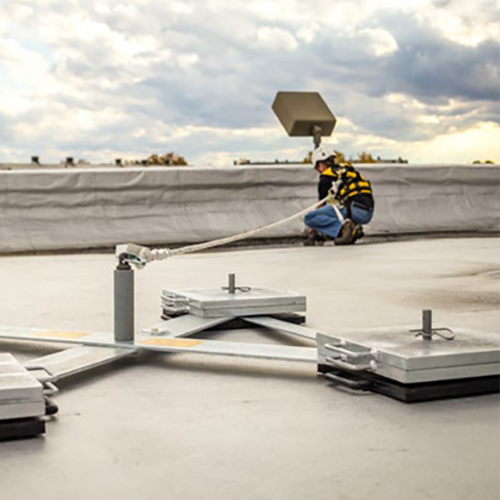 Person on a roof using equipment, with a cloudy sky in the background