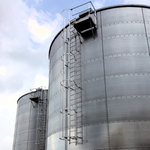 NextGen Mighty-Lite Fixed Ladder - Two large metal silos with ladders against a blue sky.
