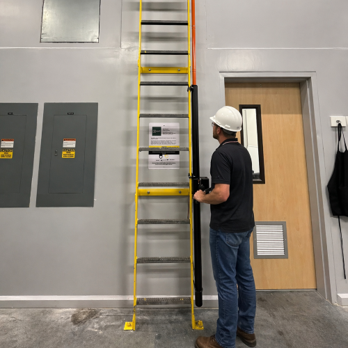 Person using a yellow ladder in an indoor setting with a door and wall panels.