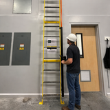 Person using a yellow ladder in an indoor setting with a door and wall panels.