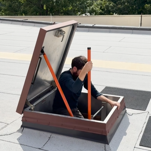 Person working on a roof access hatch with tools