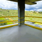 NextGen Tensioned WebRail™ - Concrete floor with a yellow safety line, concrete column, and green landscape.