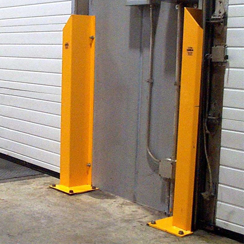 Two bright yellow metal gate safety posts installed on either side of a gray industrial door opening, with a white garage-style door in the background.