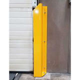 A bright yellow metal garage door stopper mounted vertically against a white roller door and textured brown wall.