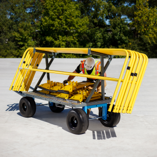 Person using a large yellow and black tool cart outdoors with trees in the background