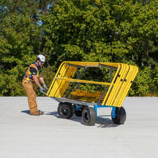 Person moving a yellow metal frame on a concrete surface with greenery in the background