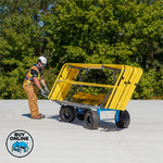 Person moving a yellow metal frame on a concrete surface with greenery in the background
